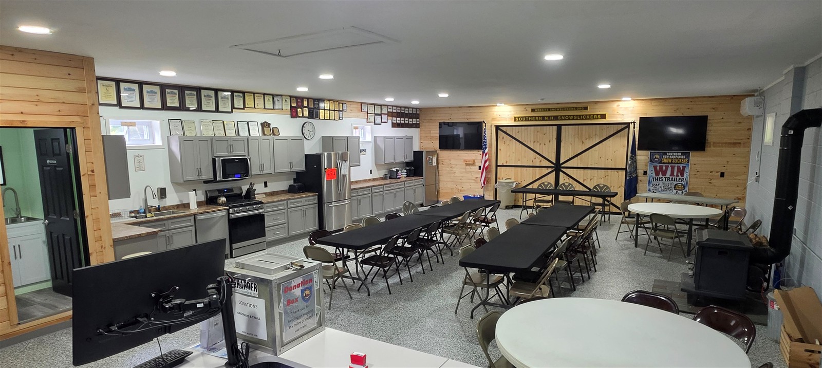 Panoramic view of the renovated Snow Slickers clubhouse with tables, kitchen cabinetry and wood accents.